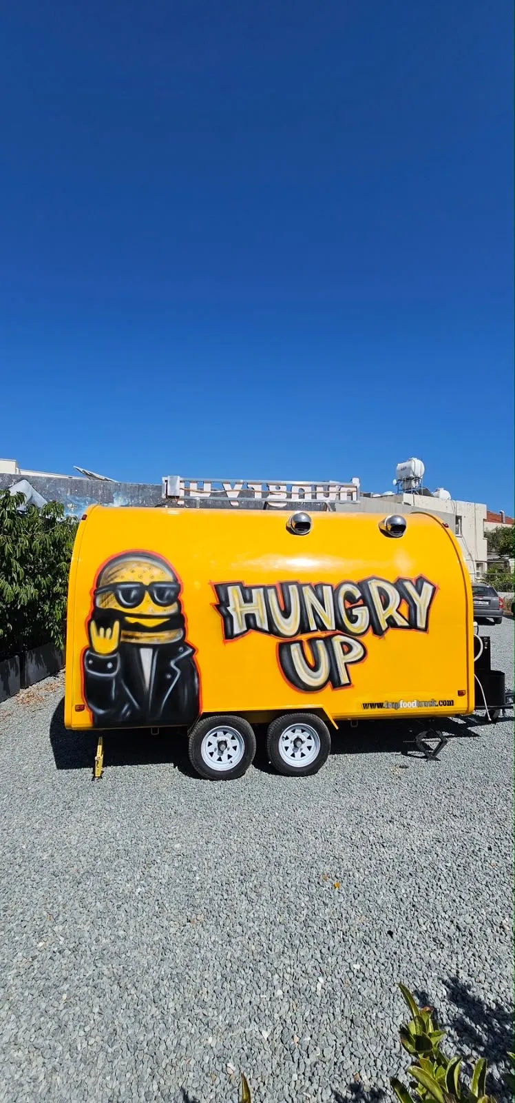 The airbrushed burger mascot in sunglasses and a leather jacket beside HUNGRY UP in bubble letters on the side of the trailer.